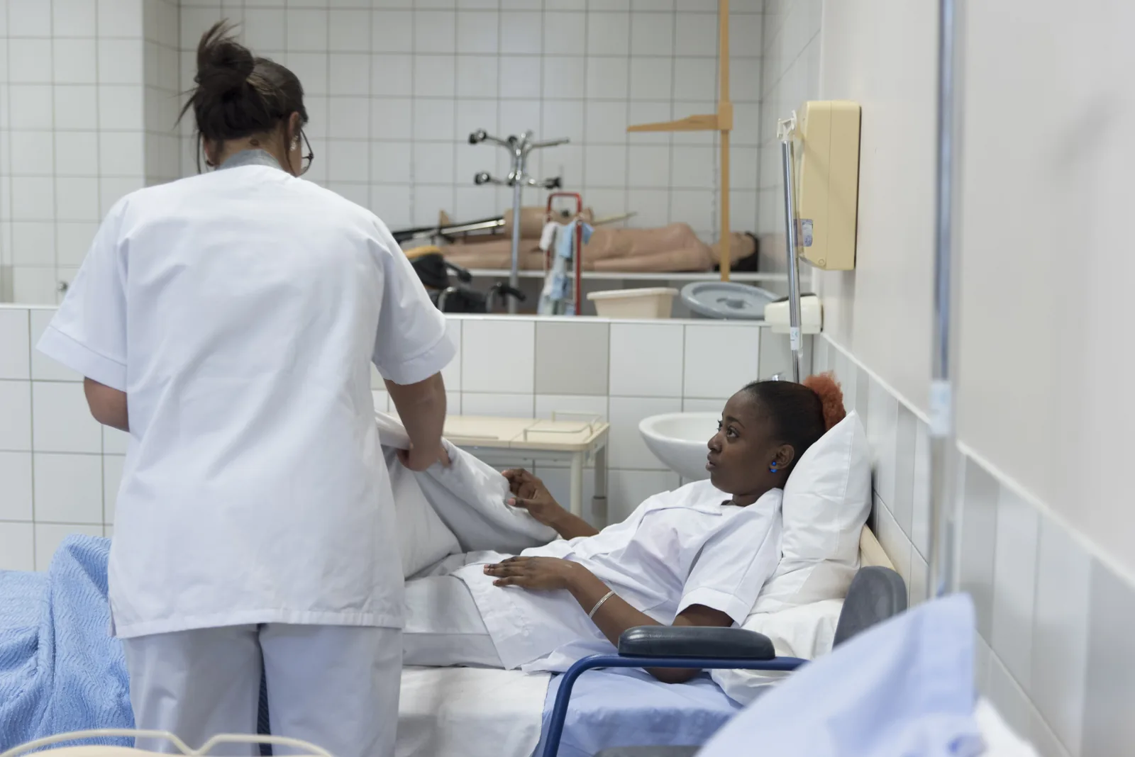 Élève aide-soignante auprès d'un patient au lit